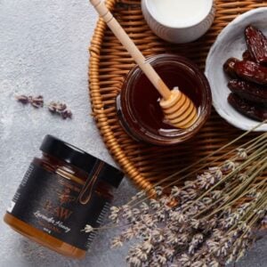 a jar of raw lavender honey placed next to a plate with dates and dry lavender