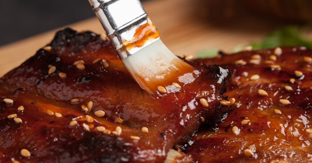 Honey barbecue sauce is brushed on grilled meat
