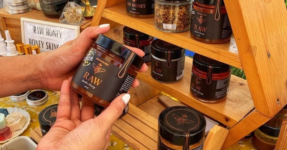 An assortment of raw honey jars with different colours and labels on a wooden